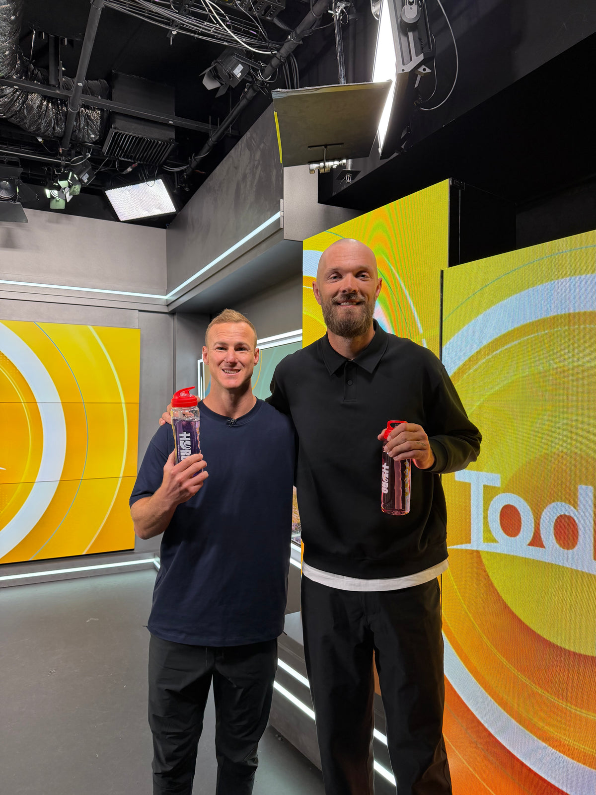 Daly Cherry-Evans and Max Gawn on the Today show set with a Hyro pouch and bottles on the desk