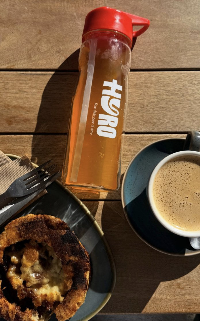 Hyro bottle next to a coffee and a pie at a cafe