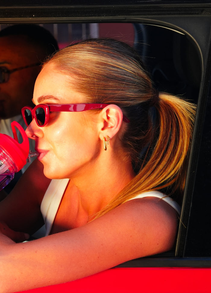 Woman drinking Hyro from a red car window