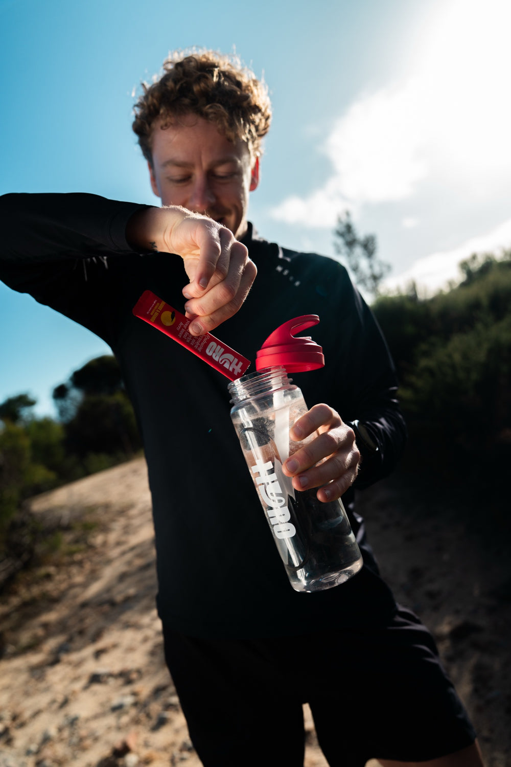 Man pouring a Hyro stick into a clear bottle outdoors in bright sun